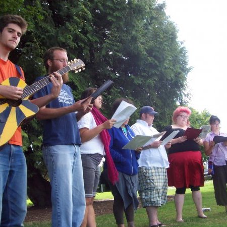 a bunch of people singing at a picnic